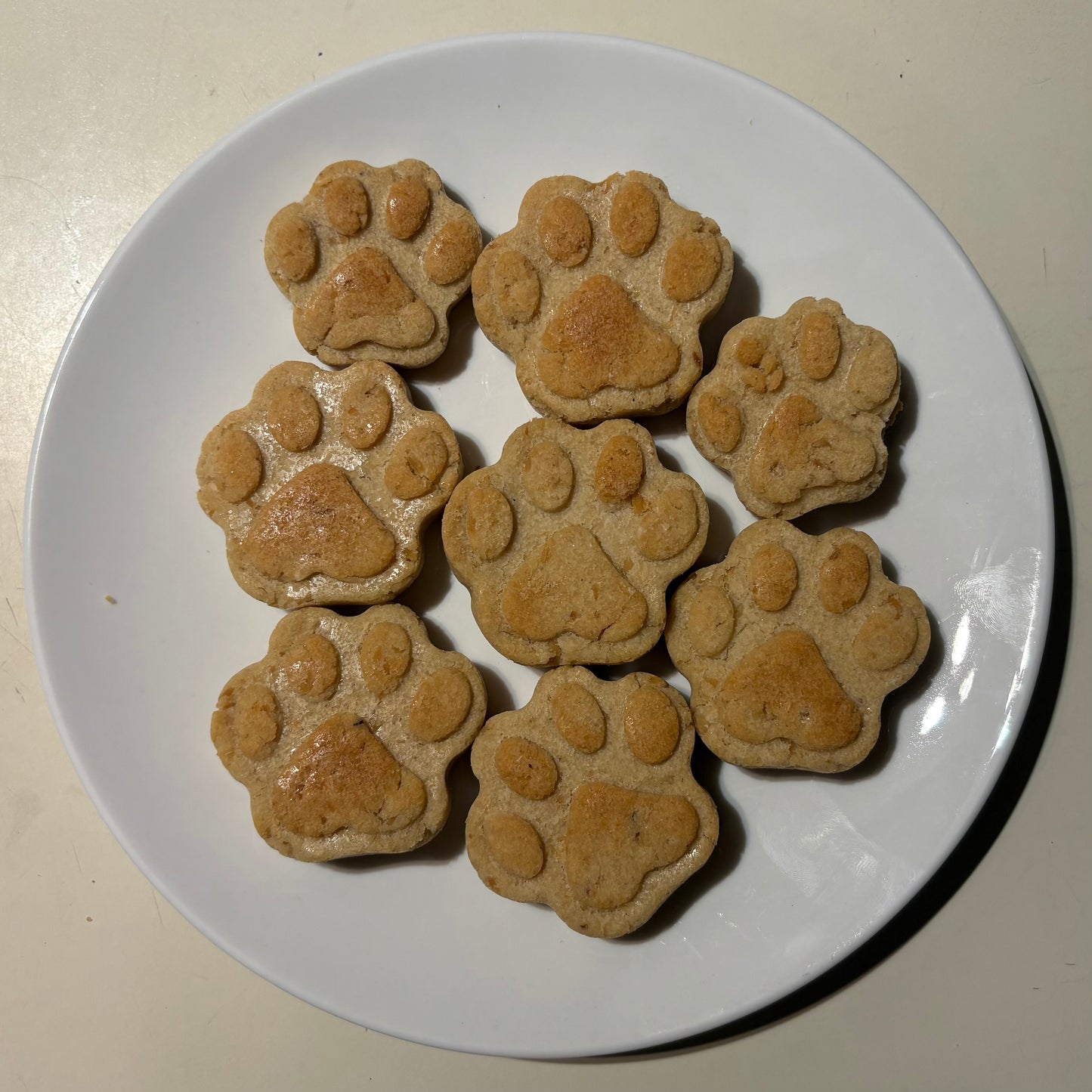 Paw shape salmon natural dog treats on a white plate