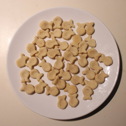 Round white plate with fish-shaped cookies on a beige surface.