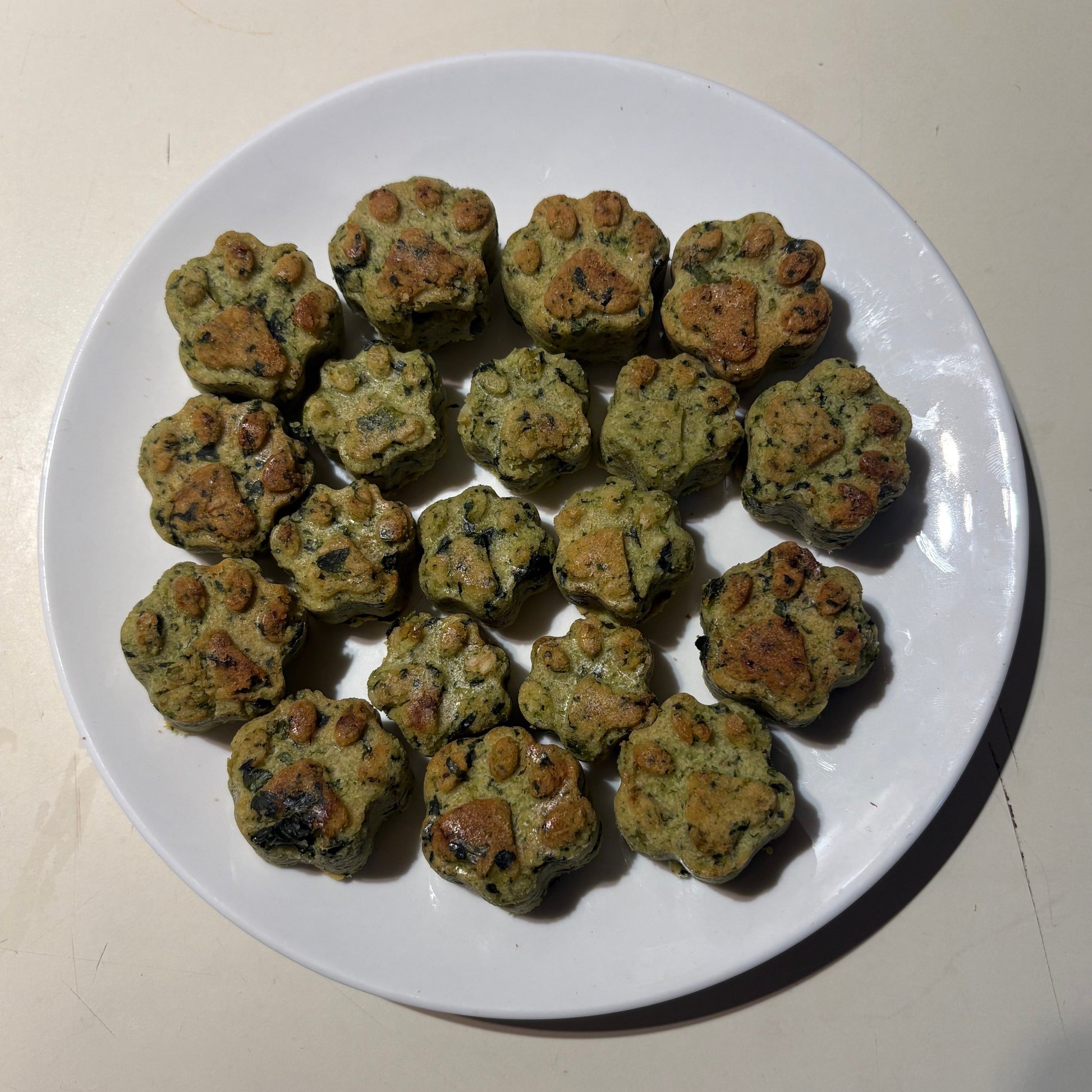 Paw shape spinach and broccoli natural dog treats on a white plate