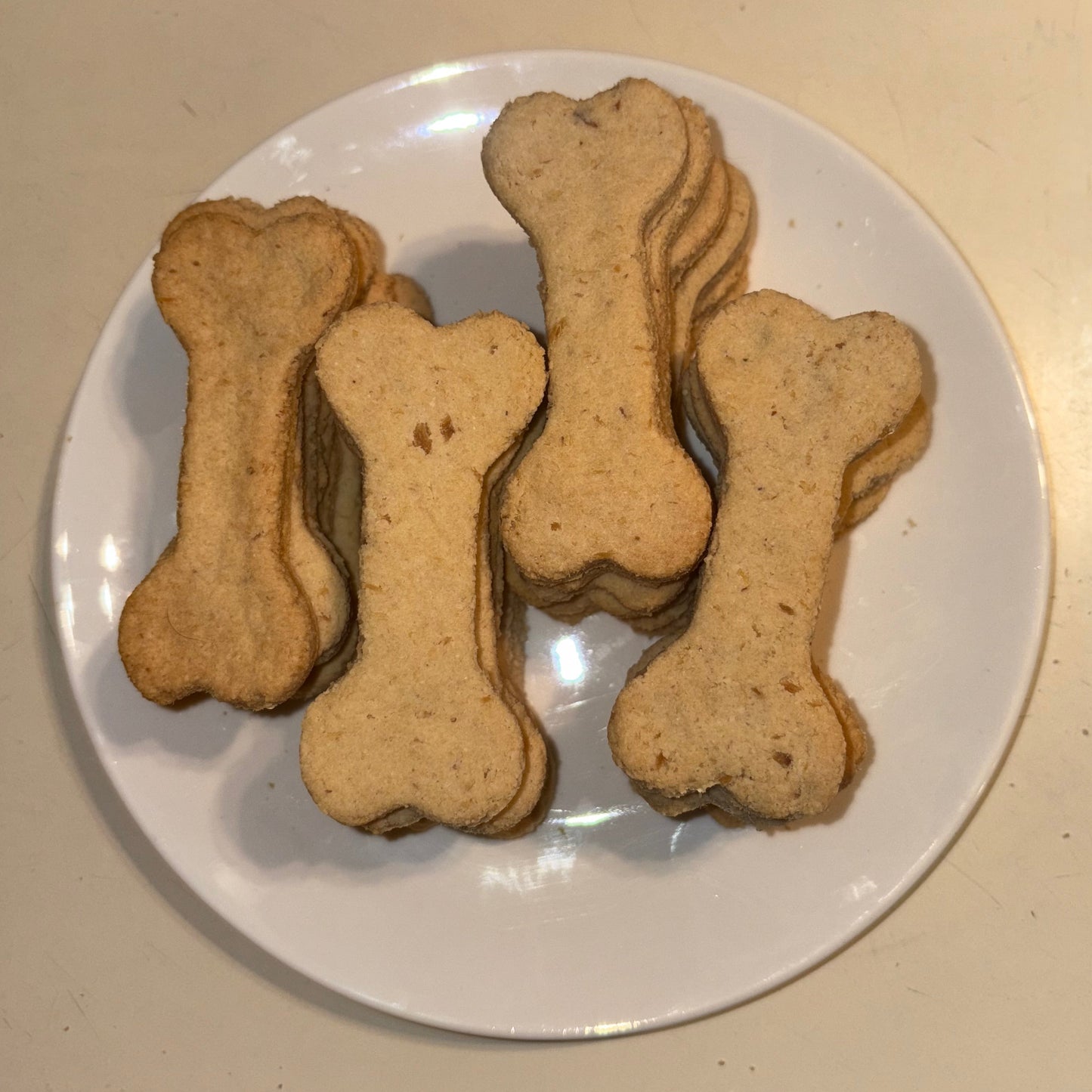 Dog bone-shaped cookies on a white plate with a beige background