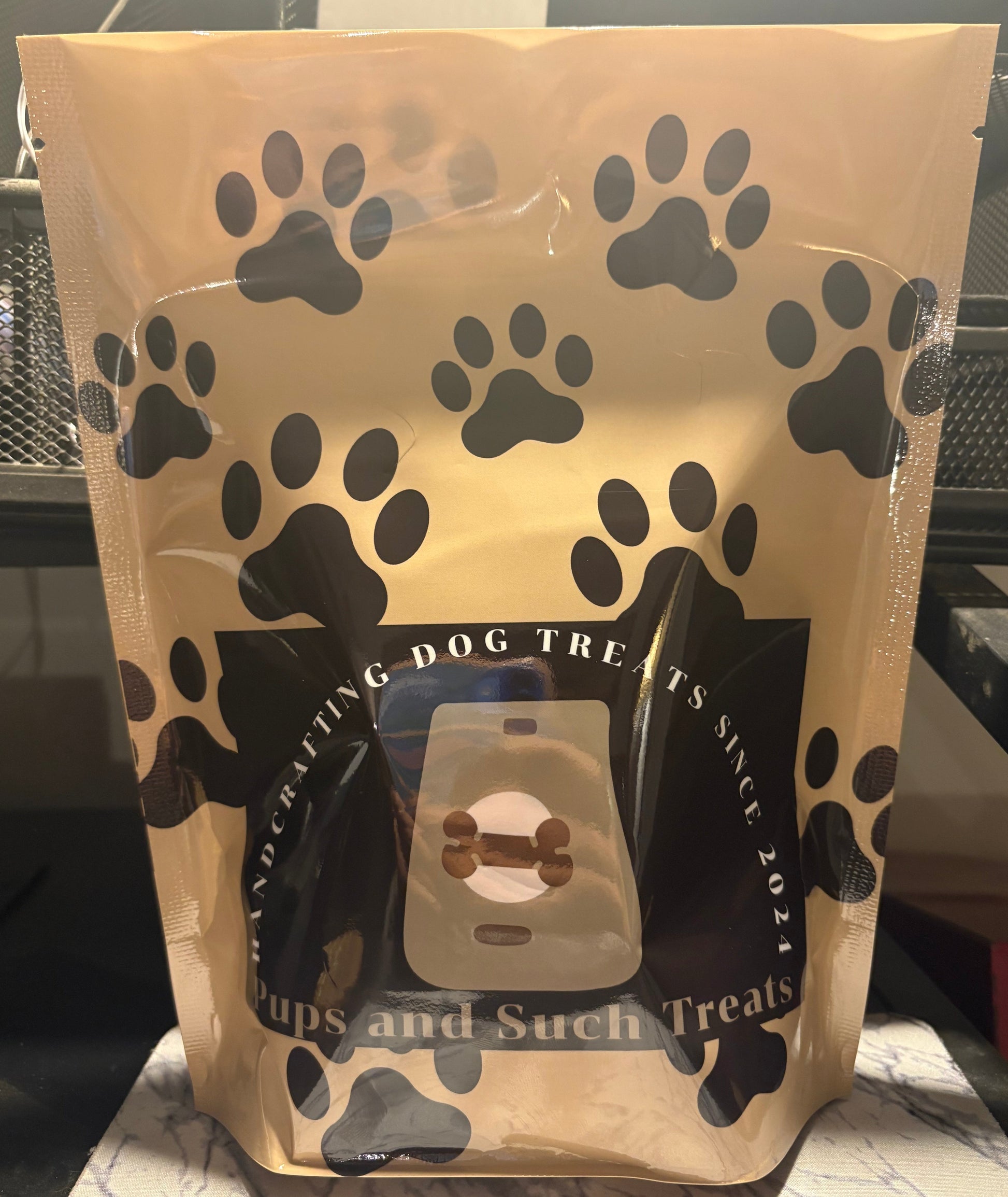 Dog treat packaging with black paw prints on a beige background
