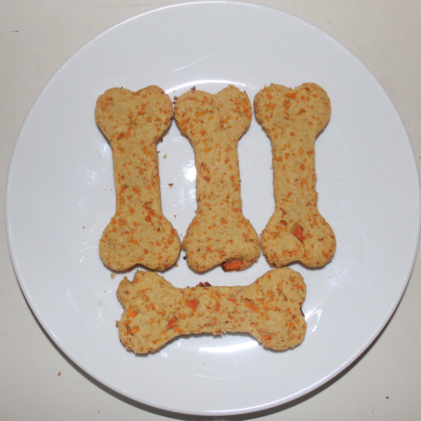 bone shaped carrot natural dog treats on a white plate