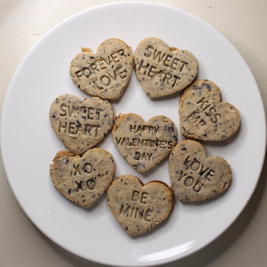 Heart-shaped cookies with Valentine's Day messages on a white plate.