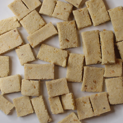 White plate with square-shaped dog treats on a beige surface